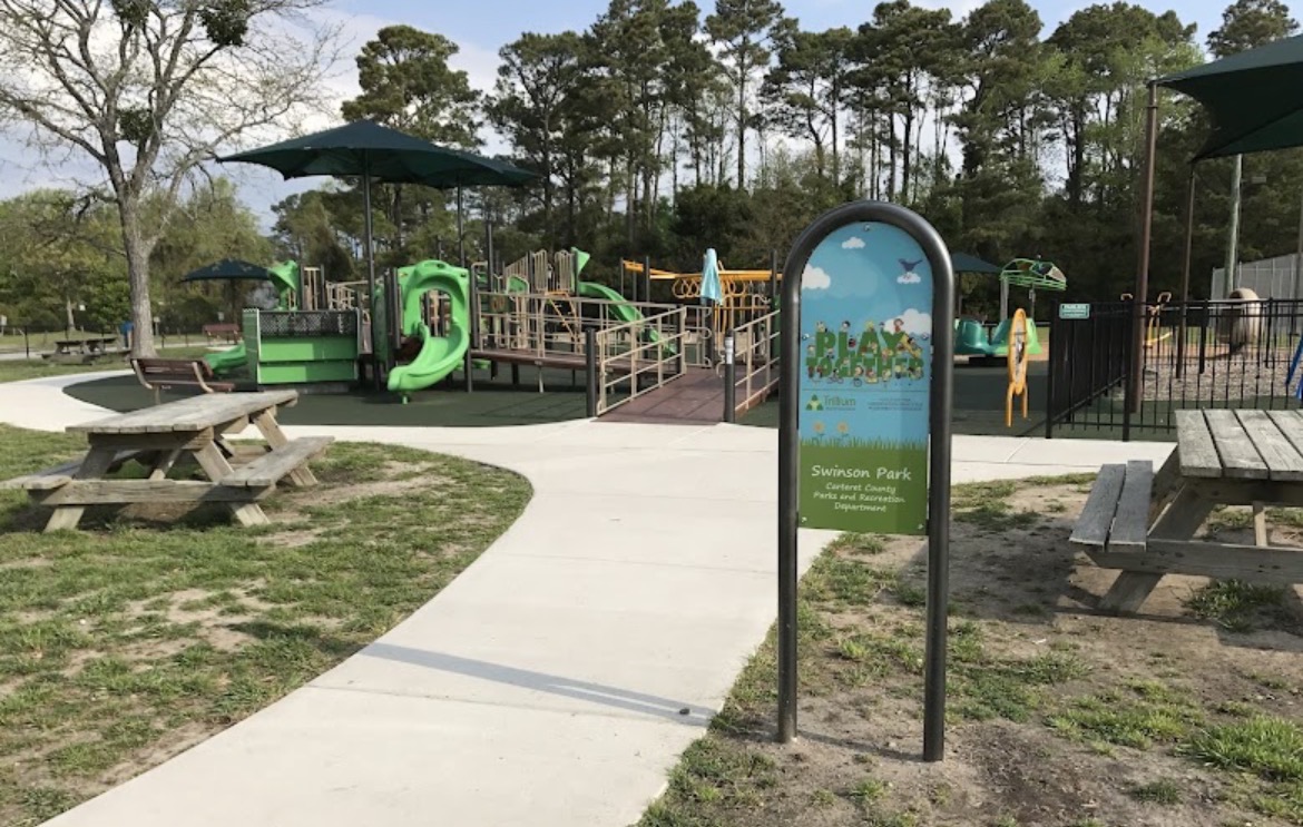 Swinson Park playground in Carteret County with green play structures under shade sails and picnic tables